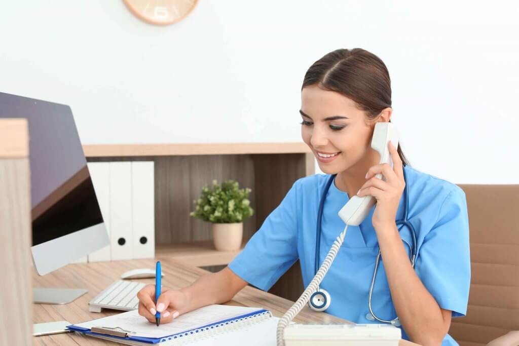 Weibliche Sprechstundenhilfe notiert Kontaktdaten bei Telefonat in der Orthopädie Zsilinszky